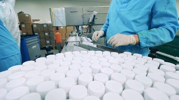 工厂工人正在把小桶搬到传送带上制药厂生产线