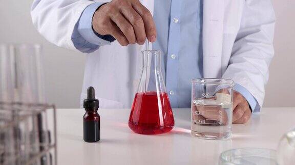 年轻科学家在实验室搅拌锥形烧瓶中的红色溶液