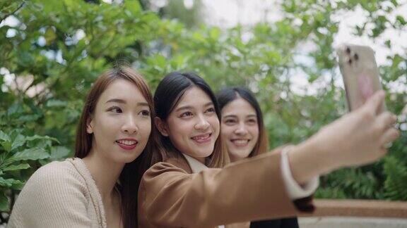 一群亚洲女学生在大学里用智能手机自拍