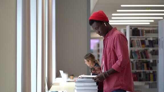 非洲男生在图书馆为研究项目做文献检索准备考试