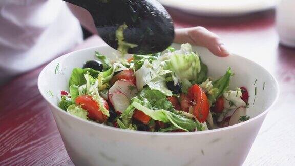 在厨房做健康的食物新鲜蔬菜沙拉素食主义者的饮食健康午餐的特写有萝卜、西红柿、生菜、香草和橄榄女人切拌沙拉