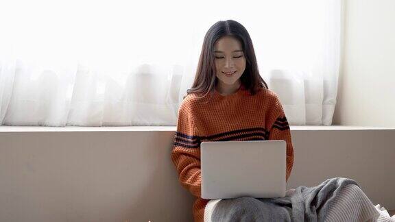 幸福自由职业者肖像亚洲女孩使用笔记本电脑而坐在舒适的地板上在家里在冬天韩国或日本女孩在家工作舒适的办公室工作场所