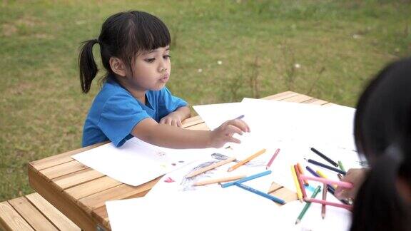 兄弟姐妹用彩色铅笔在纸上画漫画的场景教育背景股票