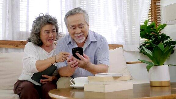 在敬老院的客厅里爷爷和奶奶坐在一起拿着手机看着手机屏幕笑得很开心