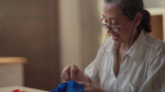 退休亚洲妇女缝纫她的衣服手工