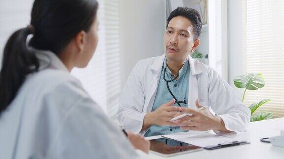 在健康诊所的会议室里成熟的亚洲男医生和年轻的女医生在讨论医学报告