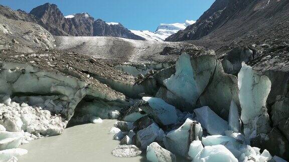 无人机俯瞰冰柱之间的寒冷池塘背景是粗糙的岩石山景观