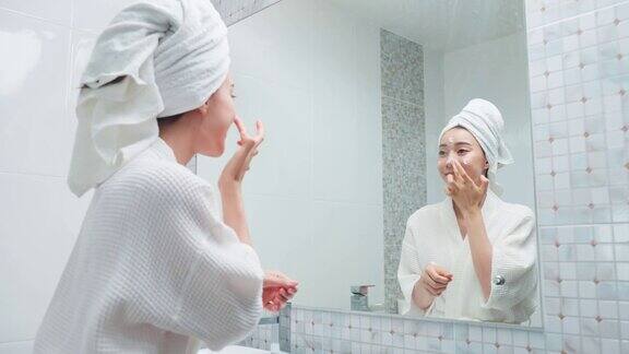 亚洲美女把光滑和皮肤护理面部柔软迷人的女性轻触面部沐浴后轻轻涂抹护肤霜恢复活力美容、护肤、养生