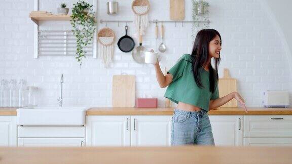 亚洲年轻女子在厨房跳舞女性在周末空闲时间快乐放松