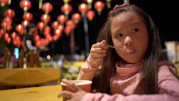 可爱的小女孩在夜市街头吃冰淇淋
