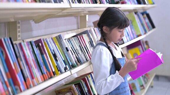 亚洲小女孩在学校图书馆看书和看书
