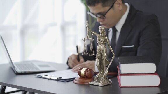 亚洲男性律师工作与锤子笔记本电脑正义女神在律师事务所在线咨询