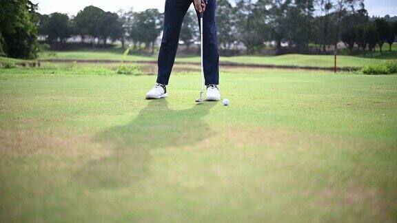 在高尔夫球场上年轻的亚洲华人男子高尔夫球击进一个洞