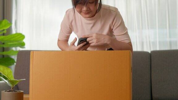 亚洲女子打开纸箱从网上购物家装拍照和检查产品