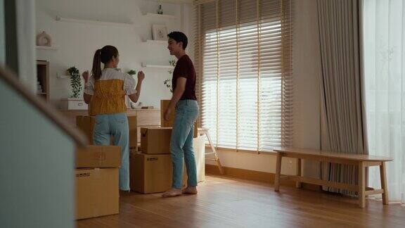 一对年轻的亚洲夫妇正在帮忙把包裹从车上搬到新房子里