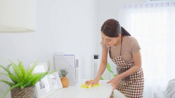 亚洲清洁服务女工清洁客厅在家里美丽的女孩主妇管家清洁工感到高兴并擦拭脏乱的工作台面为家政家务或杂务