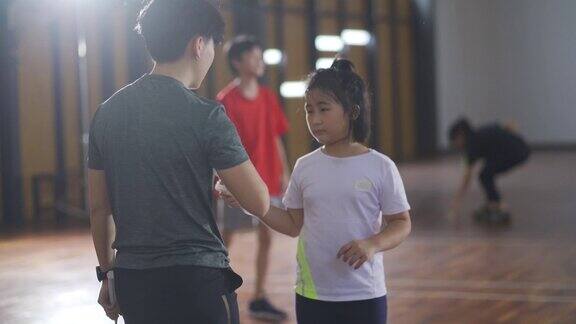 亚洲华人女羽毛球教练在羽毛球场上教她的学生