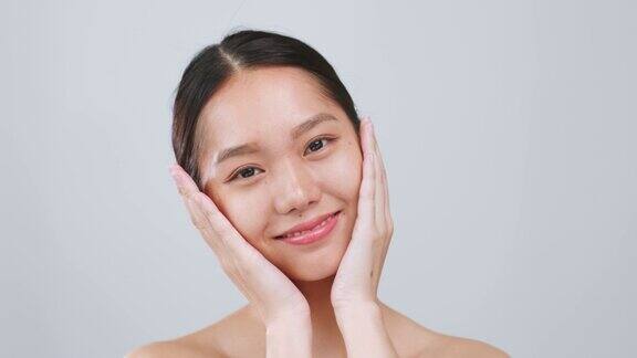 肖像年轻的亚洲美女触摸健康的面部美皮肤超过灰色的背景亚洲美皮肤