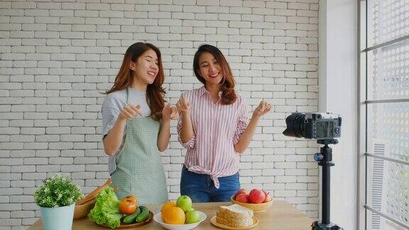 两名年轻的亚洲女性美食博主竖起大拇指并在录制视频广播视频博客健康的生活方式
