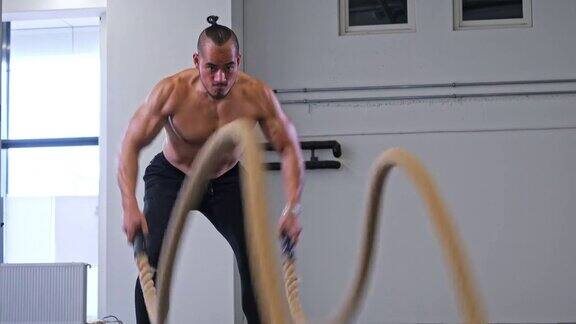 图为一名中国男子在体育馆用粗绳训练