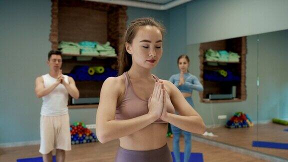 年轻的女教练在瑜伽室为人们讲授瑜伽课程