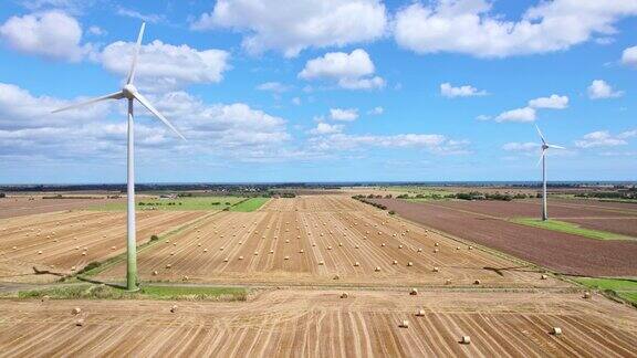 航拍画面展现了一个风景如画的景象一排风力涡轮机在林肯郡农民新收获的田地里优雅地旋转着金色的干草捆增添了乡村的魅力