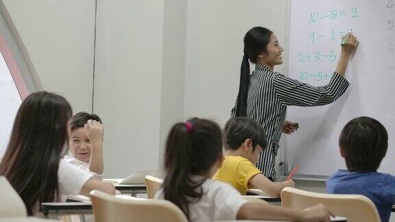 亚洲小女孩举手回答老师提问的背影幼儿园学前概念