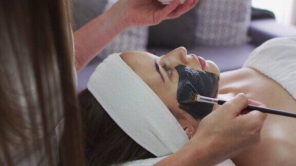 白种妇女躺下来而美容师给她一个面具