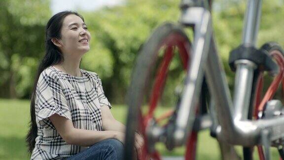 在户外骑自行车后坐着休息的亚洲妇女