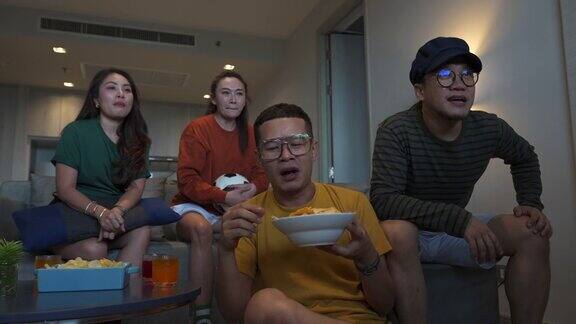 4K一群亚洲人朋友一起在电视上观看和欢呼比赛体育足球