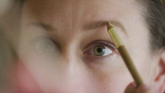 一位三十多岁的白人妇女用眉笔在眉毛上涂眉粉