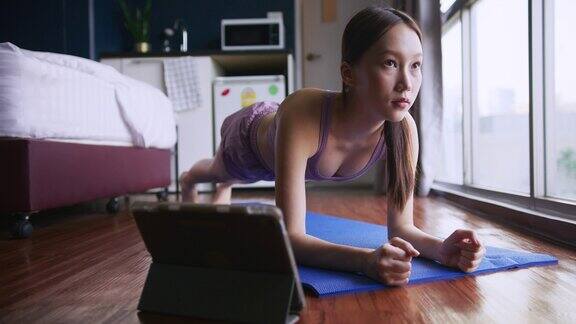 年轻女性在家锻炼在数字平板电脑上在线锻炼