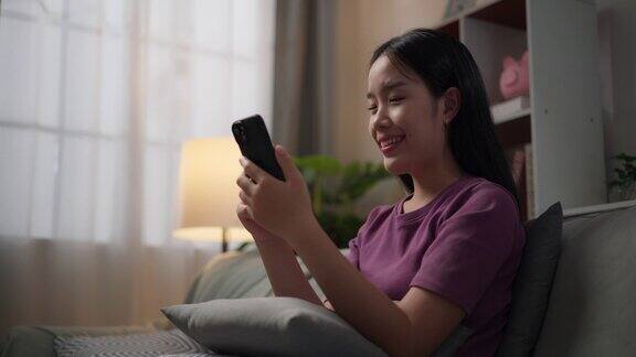 年轻的单身女性用智能手机在客厅的沙发上放松