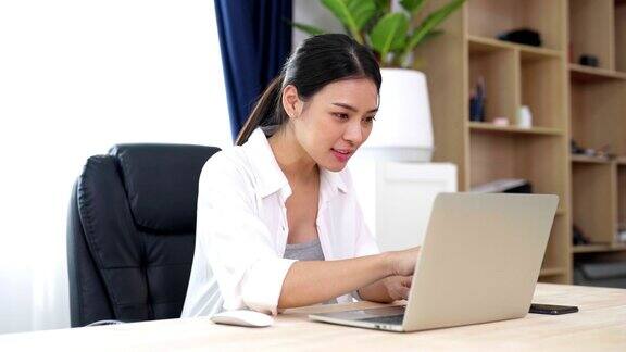 年轻的亚洲女性在家工作女性在家里的桌子上使用笔记本电脑