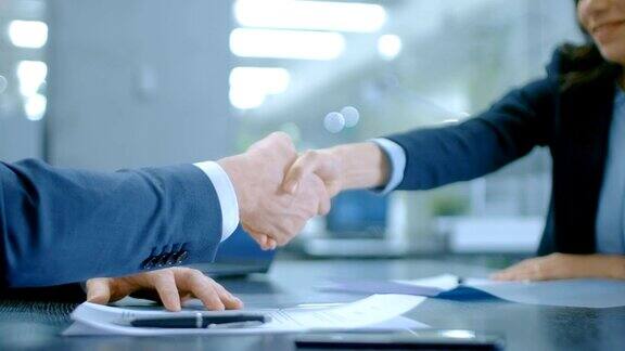 商务人士在签署合同后握手完成交易签约合作
