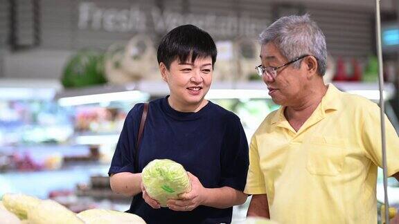 一个活跃的亚洲华人老人和他的女儿在购物和选择卷心菜