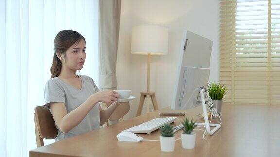 漂亮的年轻亚洲女人在家里的客厅里用笔记本电脑工作