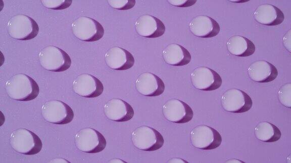 在紫色背景上移动的透明水滴的俯视图宏