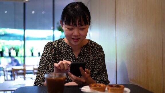 亚洲女性在咖啡馆喝咖啡休息时使用智能手机