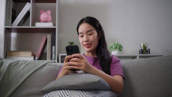 年轻的单身女性在家里的沙发上用智能手机放松