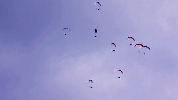 多云天空下的滑翔伞群