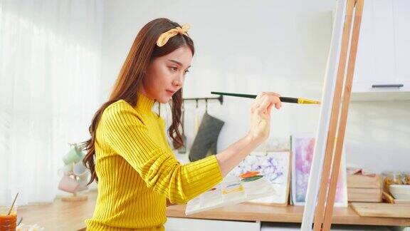 亚洲年轻有才华的女艺术家在家里的画板上着色有魅力的美女画画用水彩画和画笔创作艺术品在家享受创意活动