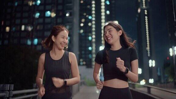 两个女运动员晚上在城市的街道上练习跑步
