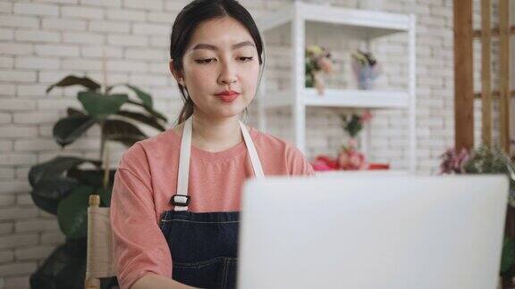 年轻的亚洲妇女正在家庭办公室的笔记本电脑上工作