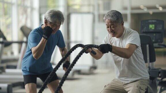 私人教练鼓励高级男子在健身房练习甩绳