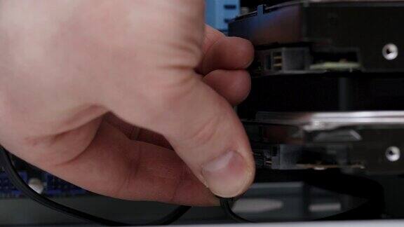 特写镜头电脑组装男性服务人员将SATA线缆连接到PC机箱内的硬盘