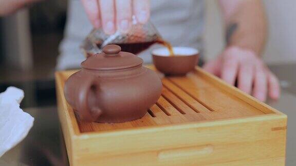 在传统的中国茶道中一名男子的手将茶从茶海中倒入碗中倒普洱茶的男人4k慢动作
