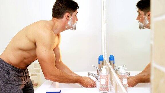 一个年轻人站在镜子前用清水洗脸