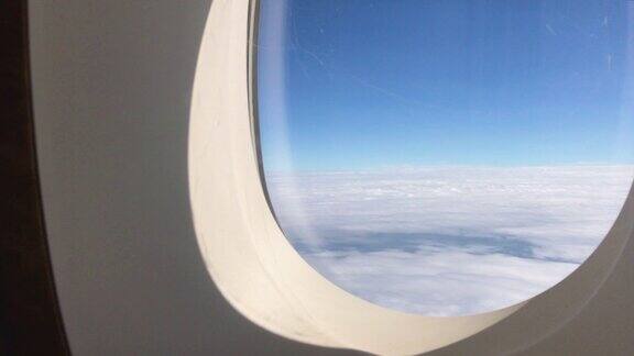 在飞机上透过窗座观看多云的蓝天