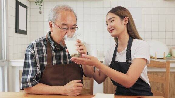 亚洲孙女和爷爷坐在厨房喝牛奶